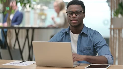 Smiling Man Working on Laptop Gives Thumbs Up