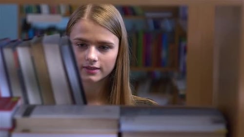 Pretty Young Girl Chooses a Book in the Library. Close Up, Slow Motion