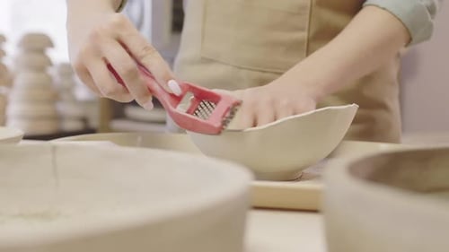 Ceramicist Refining Bowl Edge in Workshop