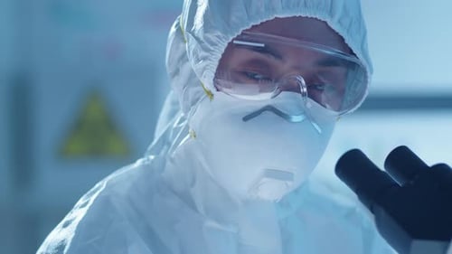 Scientist in Hazmat Suit Looking Through Microscope