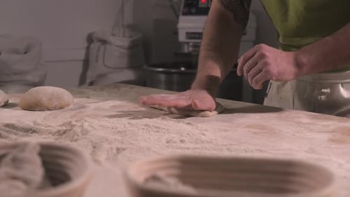Baker Hand Forming Dough on Wooden Table