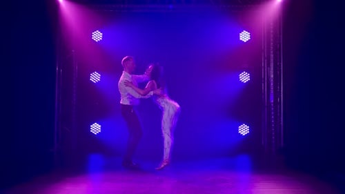 Joven pareja bailando música latina. Bachata, merengue, salsa. Grabado en un estudio oscuro con luces de neón