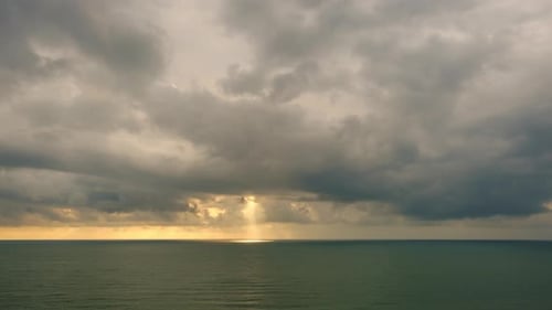 Against the background of the sea, the sun goes down, blue and orange clouds flow in sky. time lapse