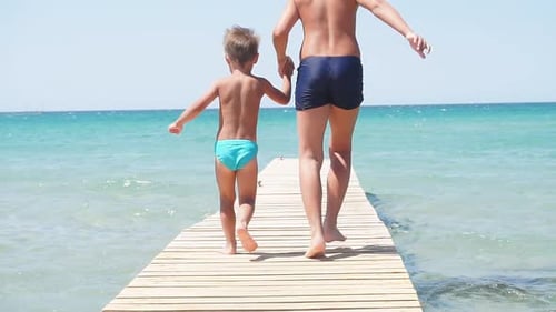 Children Dressed in Palavatelny Shorts Running To the Azure Sea Against a Blue Sky on a Sunny Day