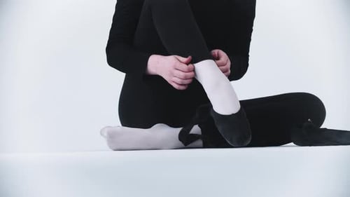 Woman Puts on Ballet Shoes in Studio