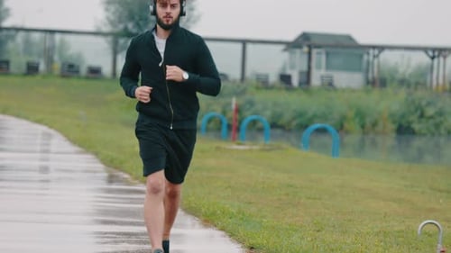 Man Running on Path Wearing Headphones Outdoors