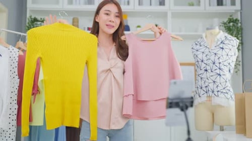 Asian beautiful woman sell cloth product online live streaming at home.