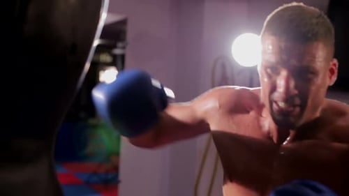 Muscular Man Boxing with Heavy Bag