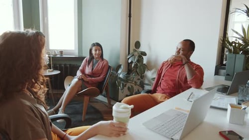 Cheerful African American Man Chatting with Two Female Colleagues in Office