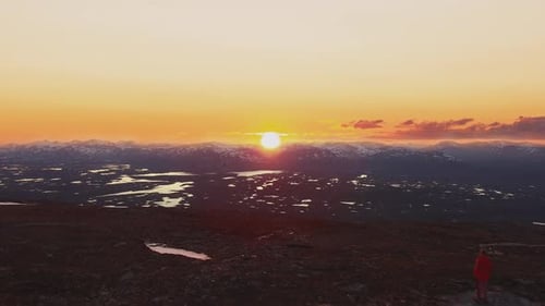 Man Standing atop Mountain Peak at Sunrise