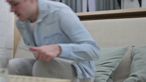 Young Adult Using Laptop on Couch Indoors