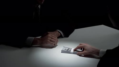 Money Exchange Between Two Dark-Suited Figures