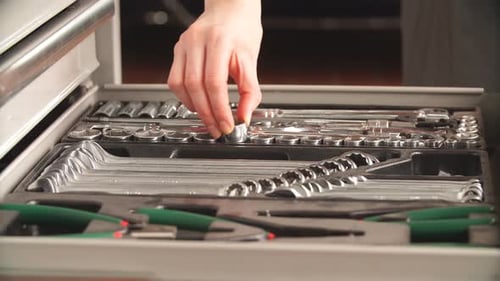 Mechanikerin nimmt Instrumente aus dem Werkzeugkasten in der Reparaturwerkstatt.