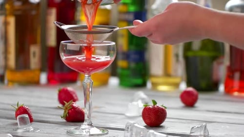 Pouring Strawberry Cocktail Through Strainer into Glass