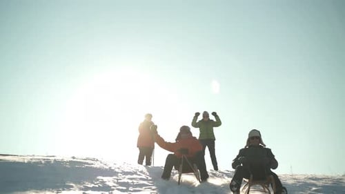 Adults Sledding Down Snow Covered Winter Hill