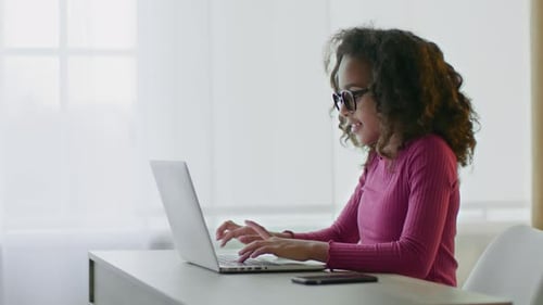 Side View Portrait of Busy Little African American Girl Typing on Laptop Computer Chatting Online