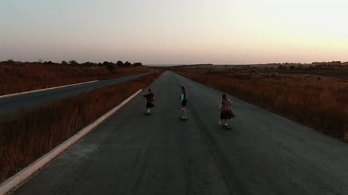 3 Young Women Are Longboarding, Colorful Sunset in the Background,