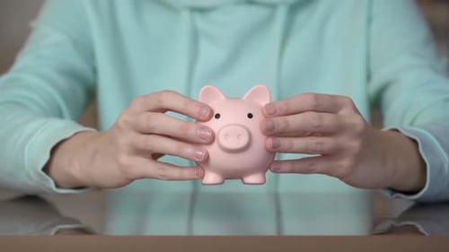 Female hands putting a piggy bank on the table. Money saving concept.