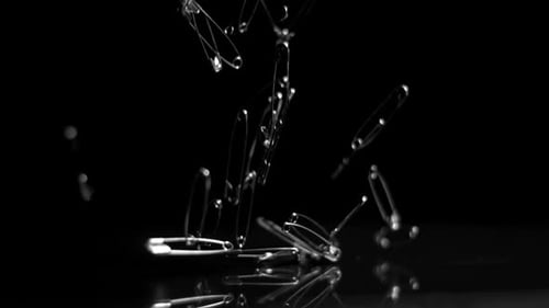 Safety Pins Falling in Slow Motion on Black