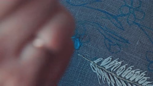 Woman's Hands Embroidering White Pattern on Gray Cloth