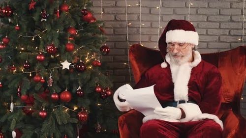 Papá Noel con gafas sentado y leyendo una carta de cerca