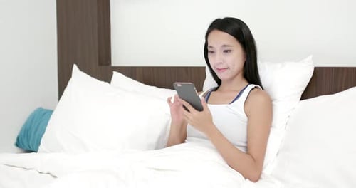 Woman Using Smartphone in Bed