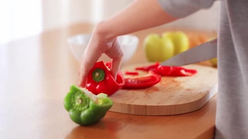 Hands Slicing Red Bell Pepper on Cutting Board