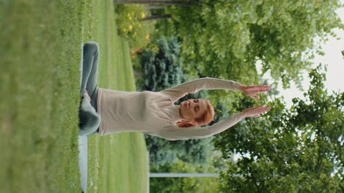 Vertical Screen Woman practices yoga and relaxing in the park