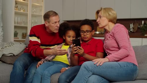 Family Gathers on Couch to Look at Smartphone