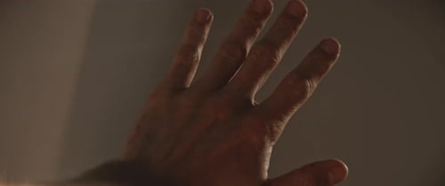 Hand Reaching Toward Light in Dark Room
