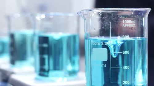 Blue Liquid Mixing in Science Laboratory Beakers