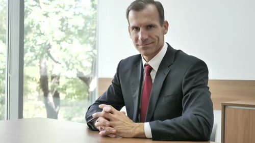 Man in Suit at Desk Gives Thumbs Up