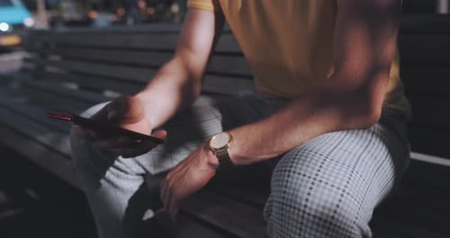 Man uses phone while on park bench