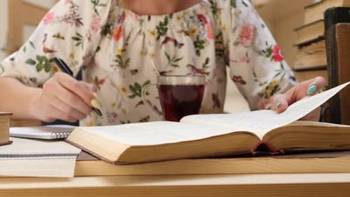 Studentische Frau liest Buch und schreibt Informationen in Notizbuch