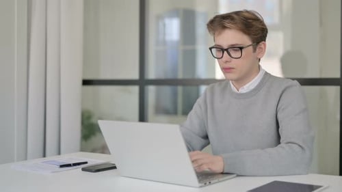 Young Adult Working at Computer Gives Thumbs Up