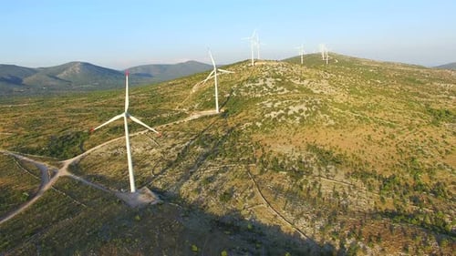Aerial view of windmills with rotating blades on a sunny day