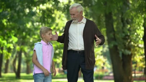 Boy Talking to Senior Man in Park