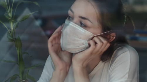 Young Woman in Mask Looking Out Window