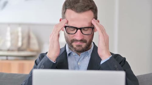 Close Up of Young Businessman with Laptop Having Headache