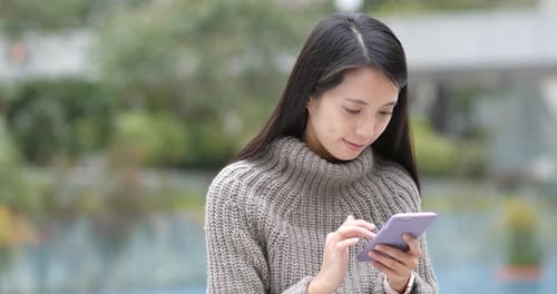 Woman Uses Smartphone Outdoors in an Urban Setting