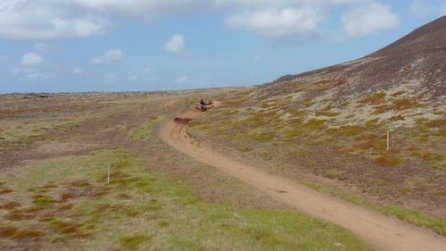 Aerial View Following Man Doing Motocross Over Hill on Iceland