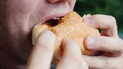 Mouth of an Adult Male Greedily Eating a Hamburger