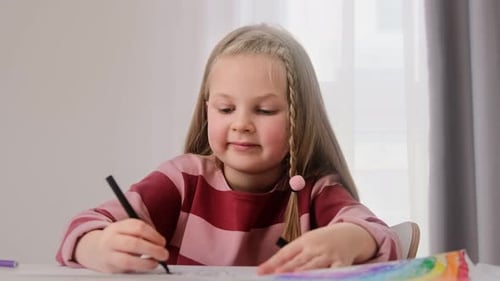 Girl Drawing Pictures with Marker at Table Indoors