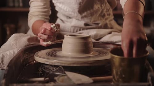 La jeune femme Potter se mouille les mains et forme l'argile avec ses doigts