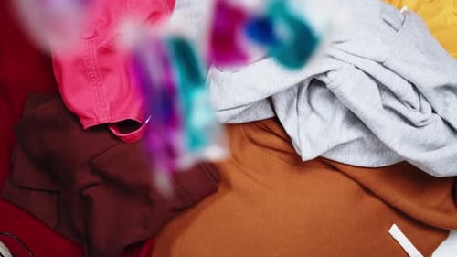 Colorful Laundry Detergent Pods Falling on Folded Clothes