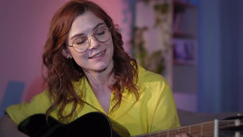 Woman Playing Acoustic Guitar at Night Indoors