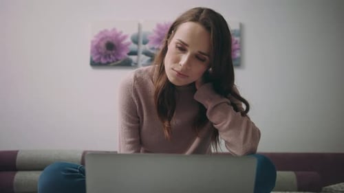 Tired Woman Watching Online News at Laptop Computer