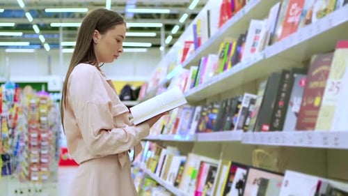 Young Lady is Buying a Book in a Store