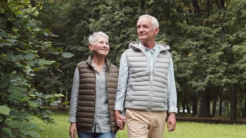 Elderly Couple Holding Hands Walking in Park