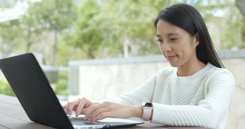 Frau tippt im Freien auf Notebook